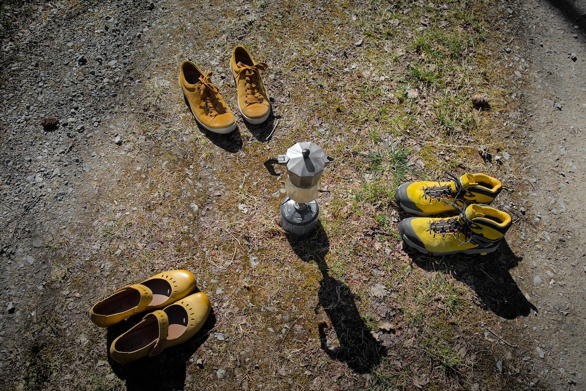 Drei gelbe Schuhe um eine Kaffeekanne herum
