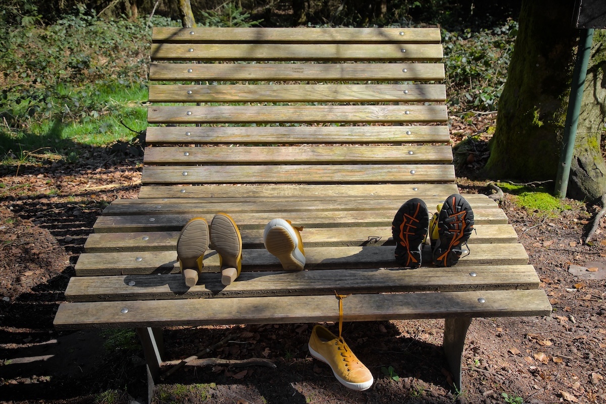 Drei gelbe Schuhe machen Pause auf einer Bank in der Sonne