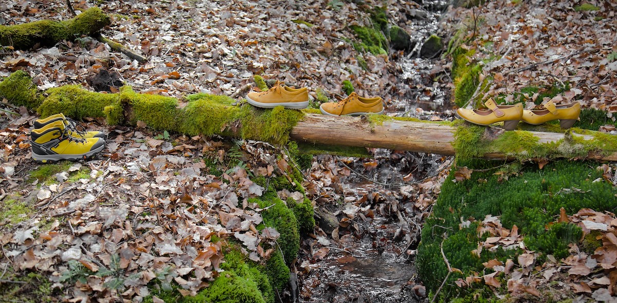 Drei gelbe Schuhe balancieren über einen Baumstamm